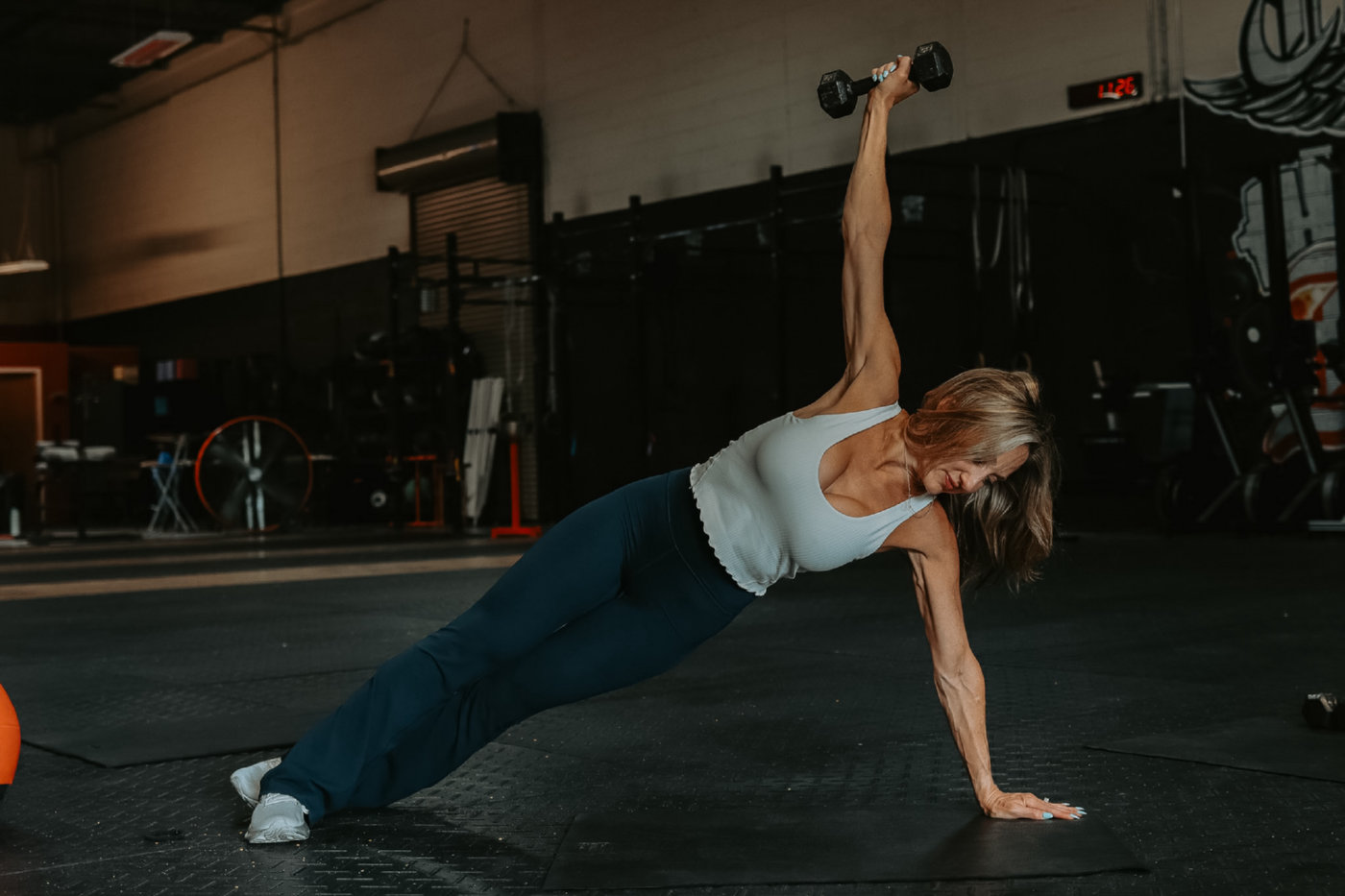 Brenna holding a side plank with a dumbbell